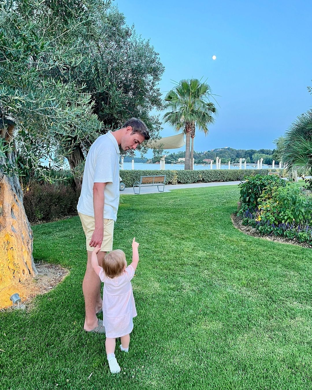 a man and a little girl are standing in the grass