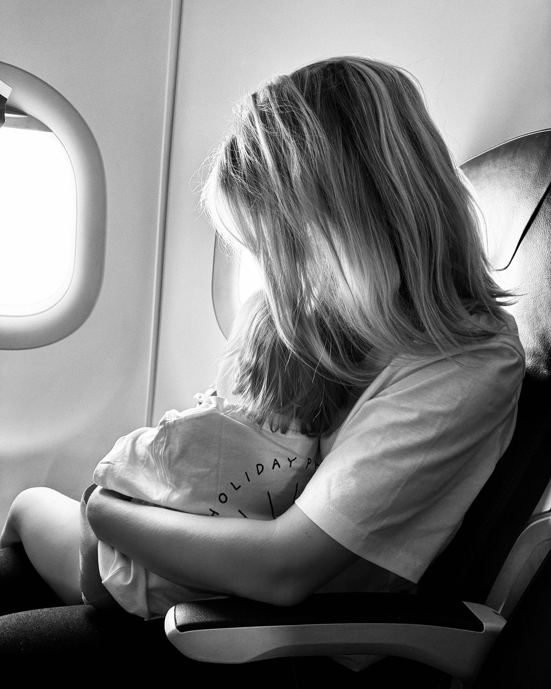 a woman is holding a child who is wearing a shirt that says holiday