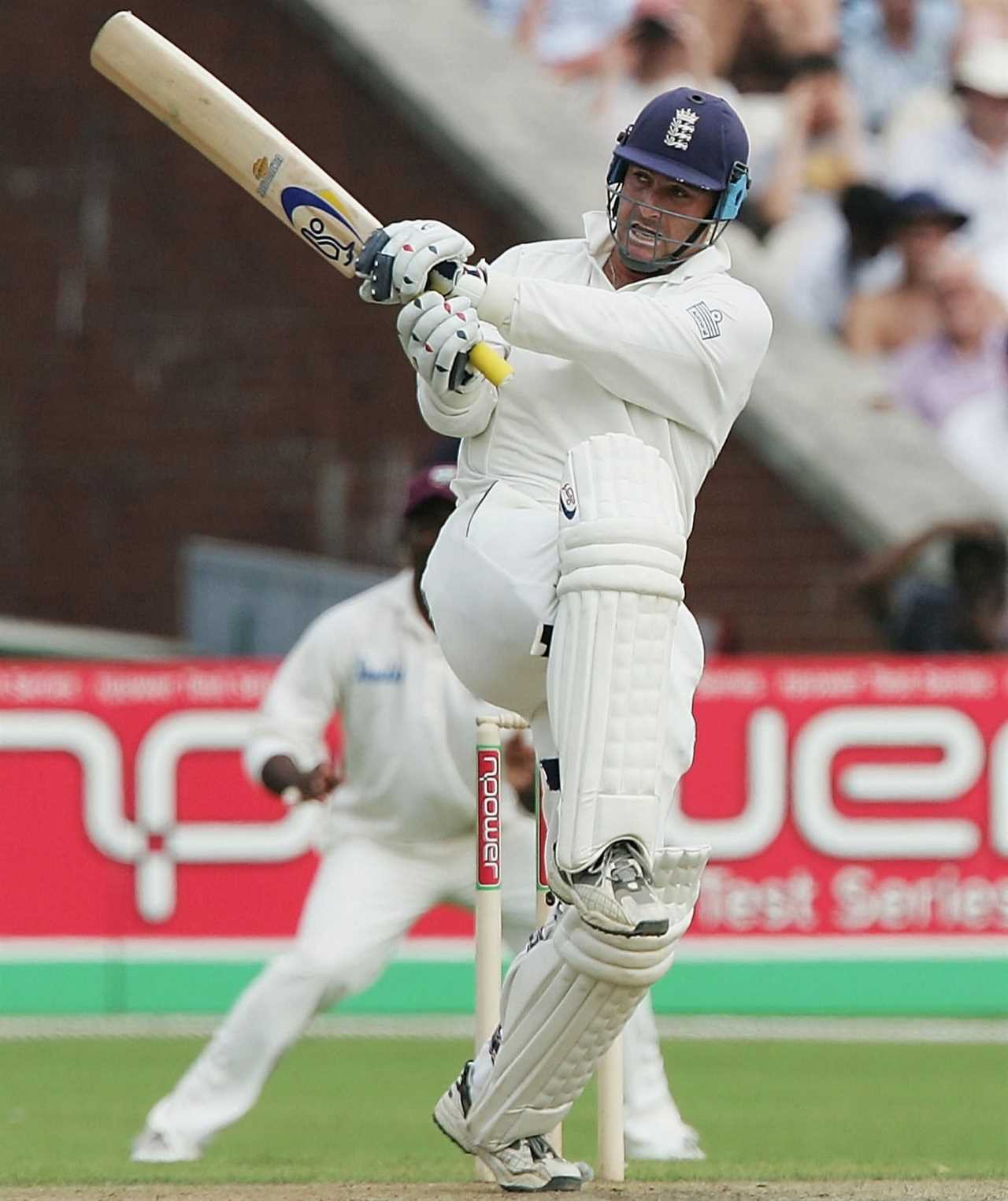 a cricket player is swinging a bat in front of an ad for fuel