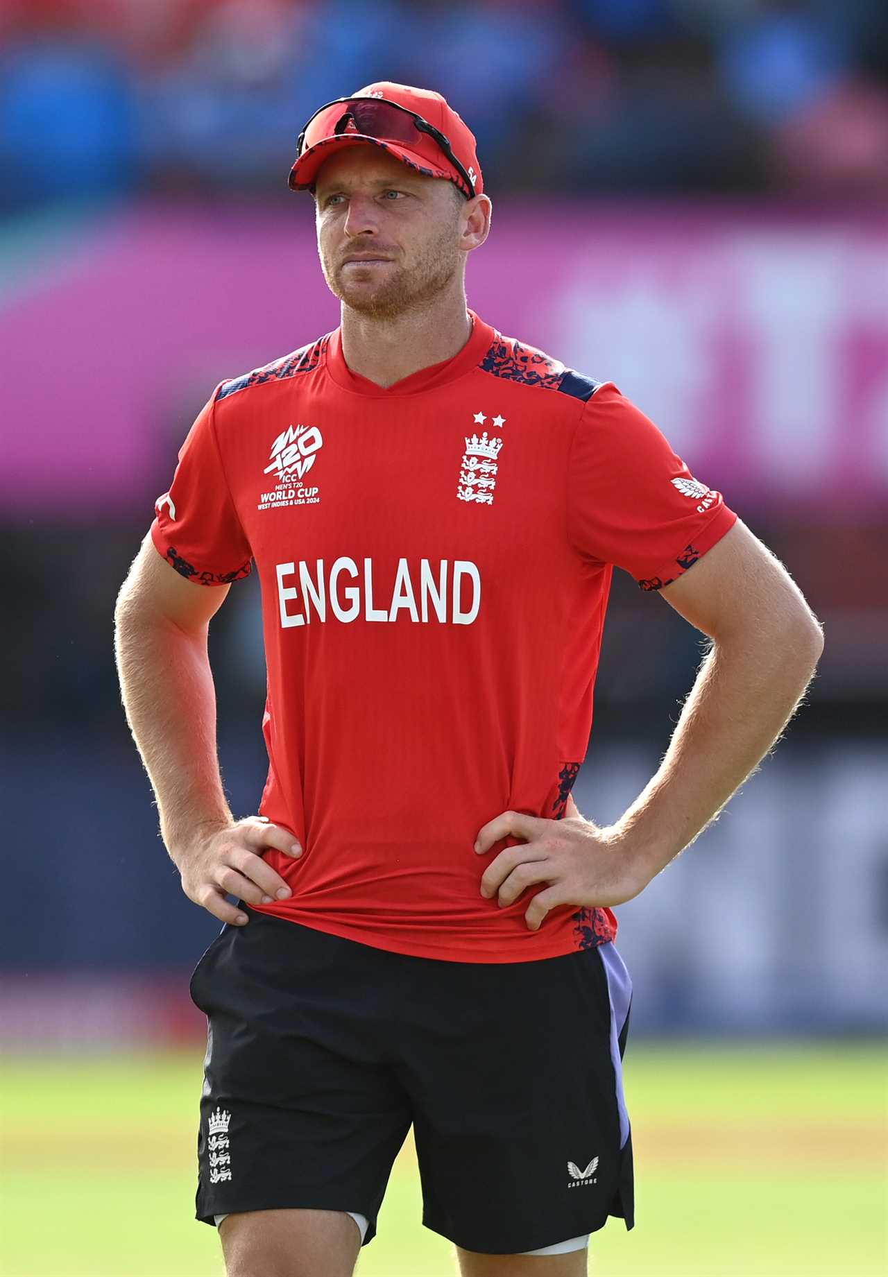 a man wearing a red england shirt stands with his hands on his hips