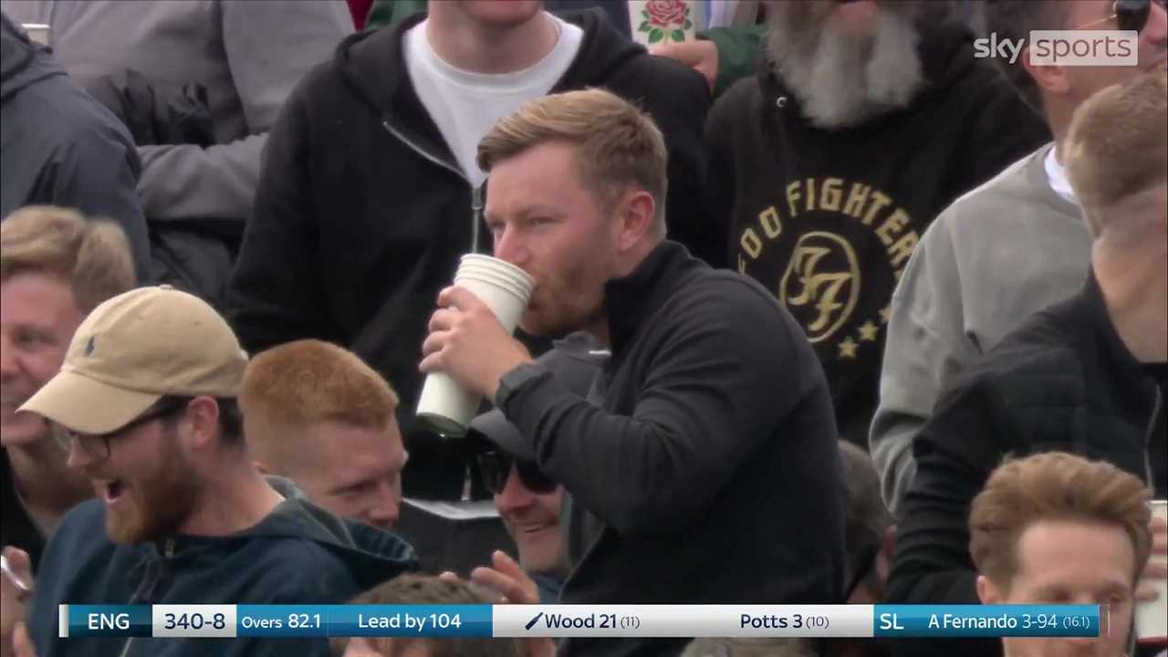 a man in a foo fighters shirt drinks from a cup