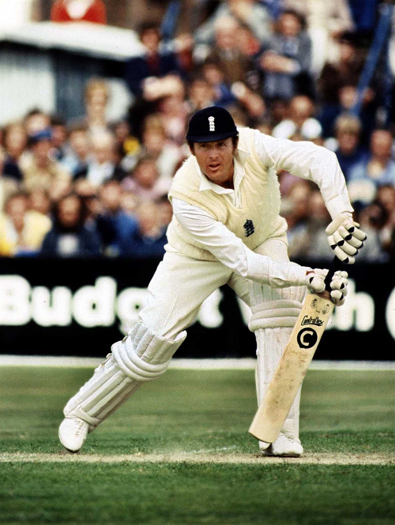 a man playing cricket in front of an advertisement for budweiser