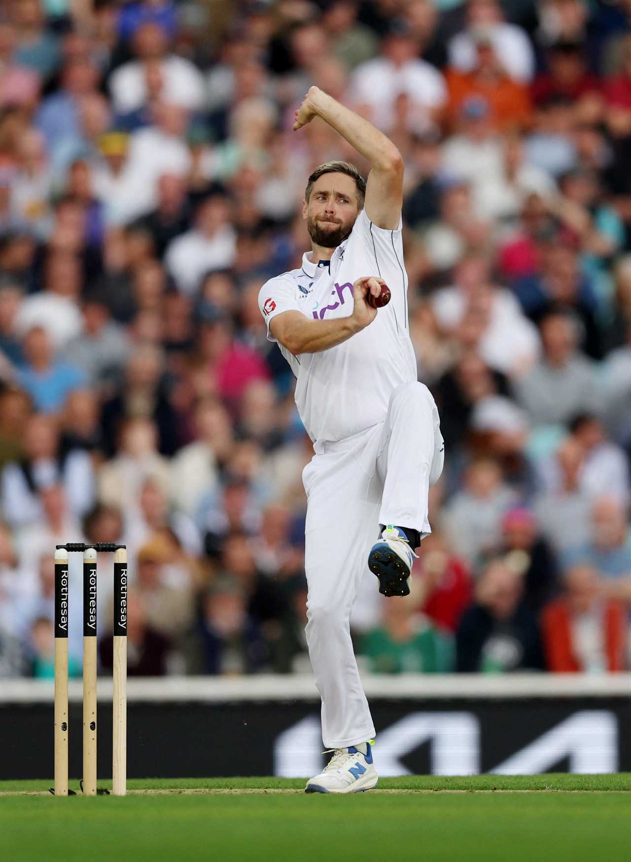 a cricket player throws a ball while wearing a white shirt with the word rcb on it