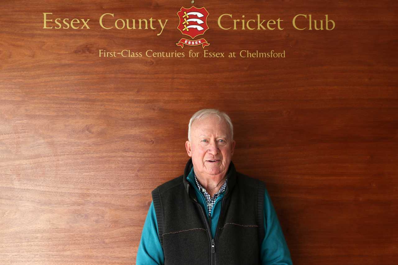 a man stands in front of a wall that says essex county cricket club