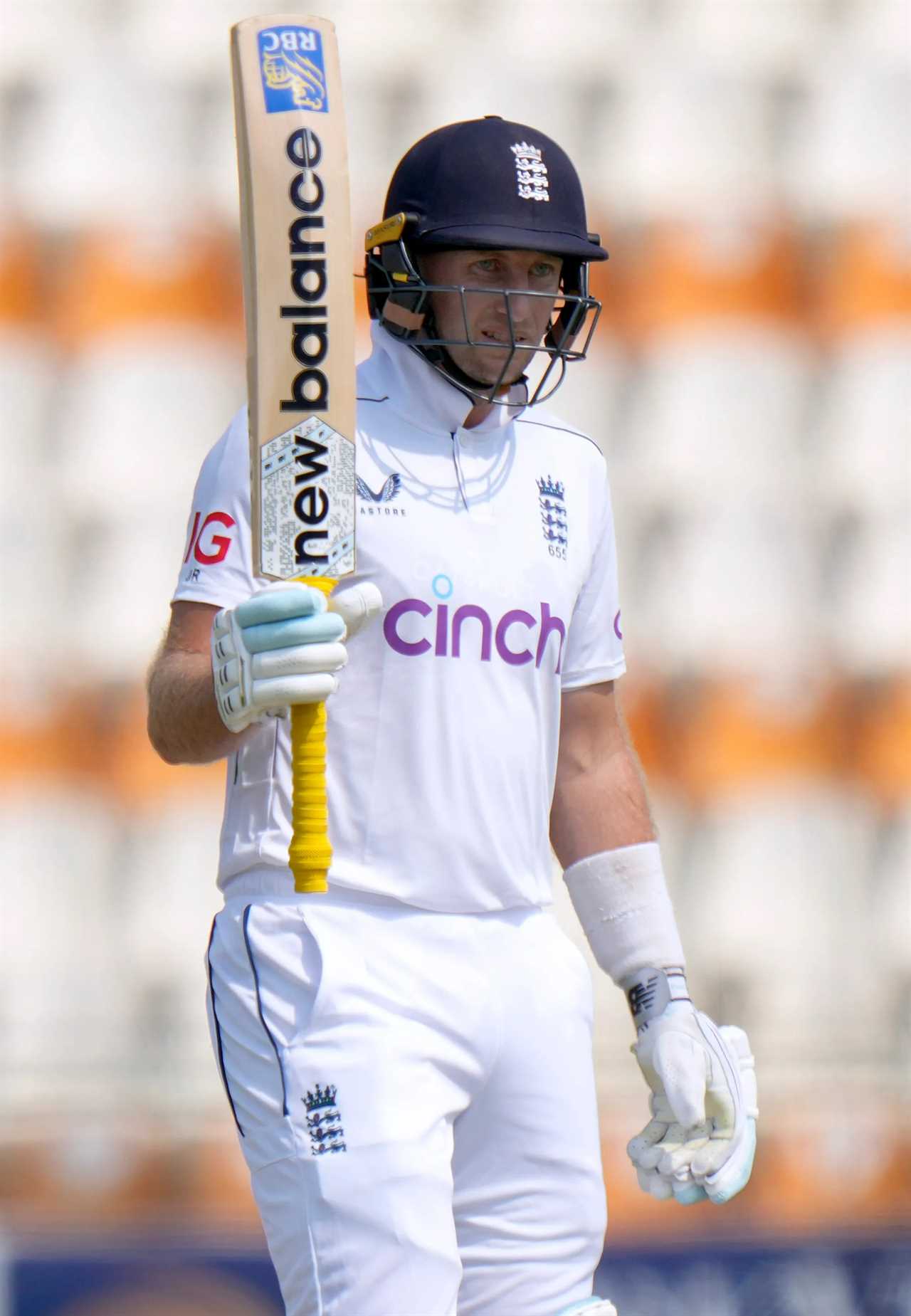 a cricket player wearing a cinch shirt holds up his bat