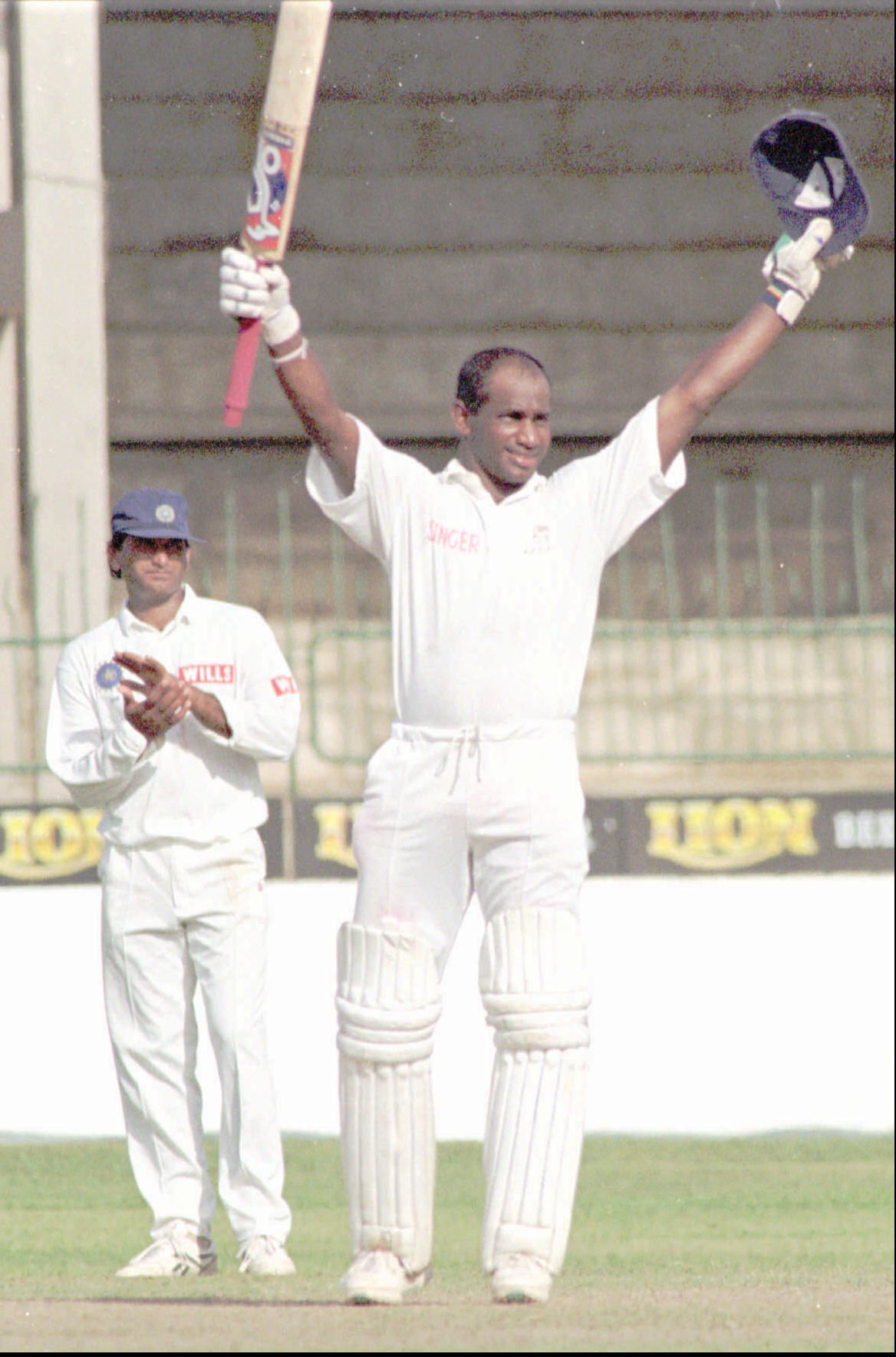 a man in a lancers shirt holds up his bat