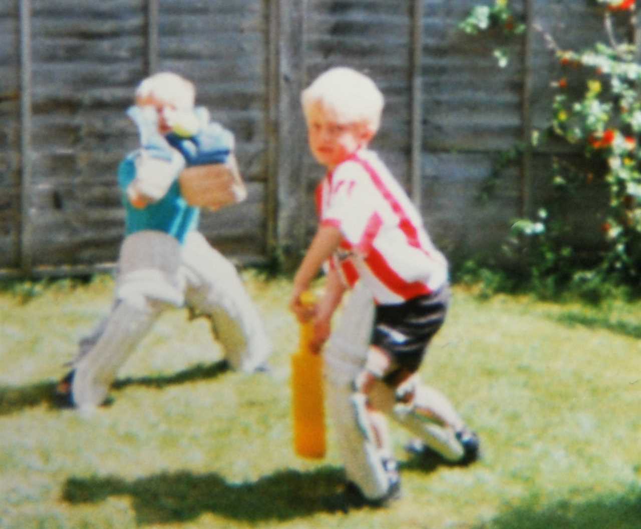 two young boys are playing a game of cricket in a backyard