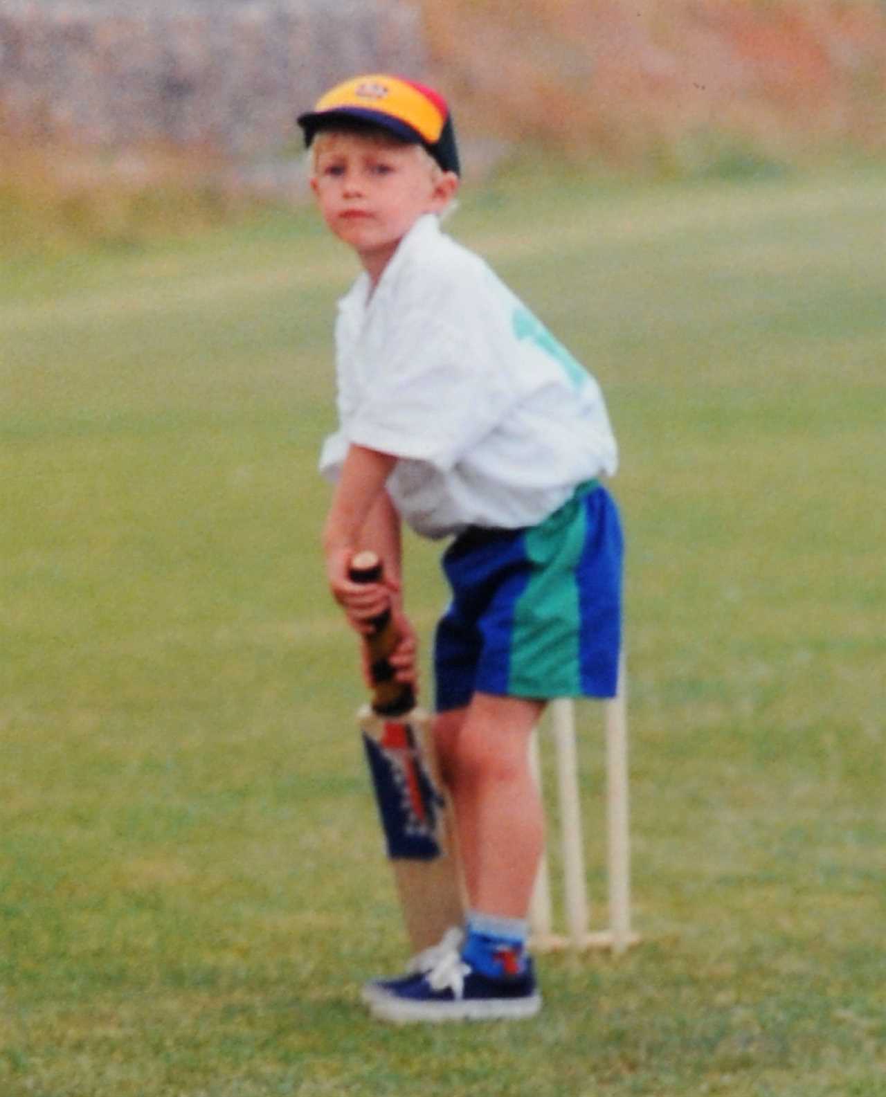 a young boy is holding a cricket bat that says ' slazenger ' on it