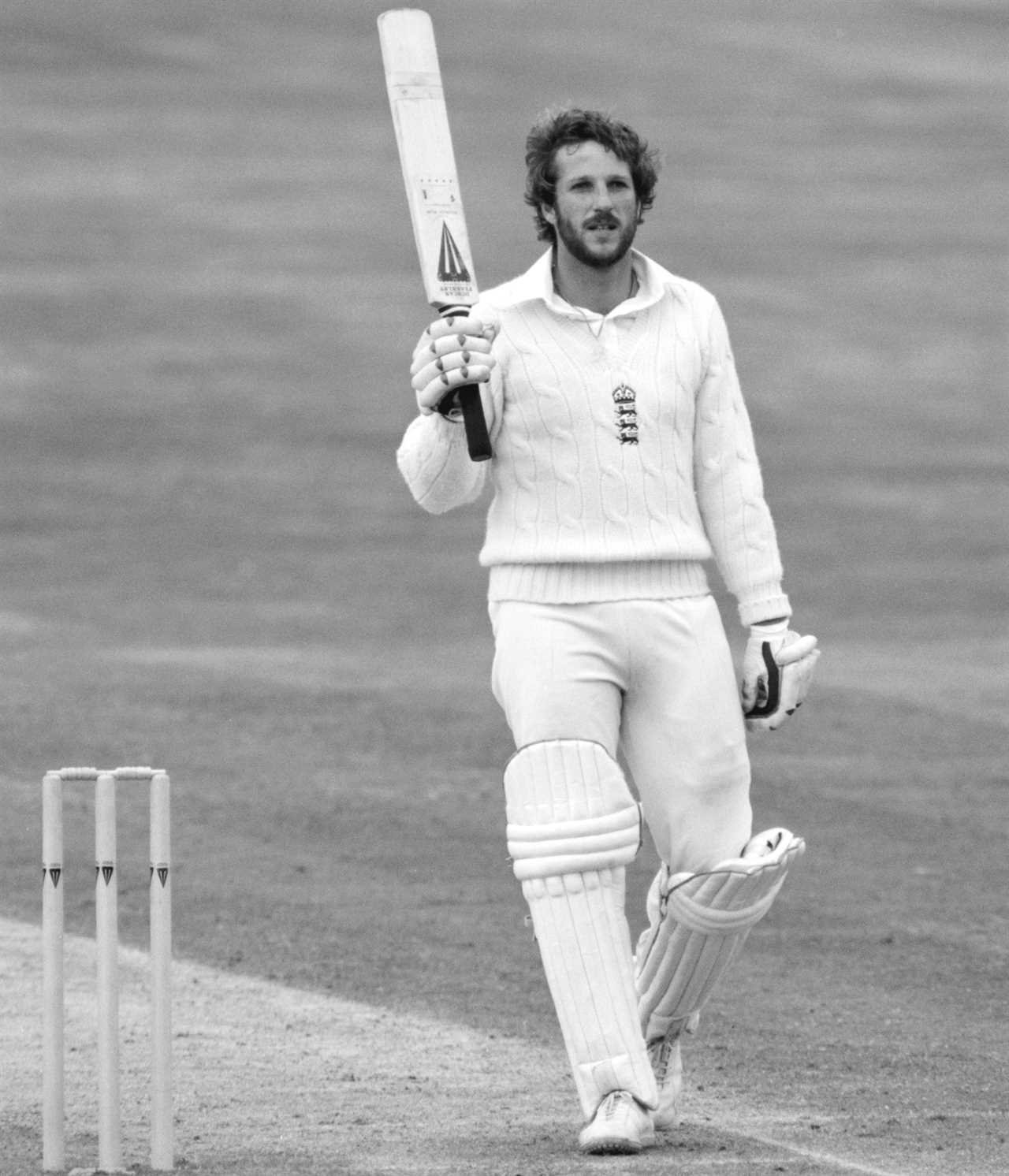 a man holding a cricket bat with the letters tb on it