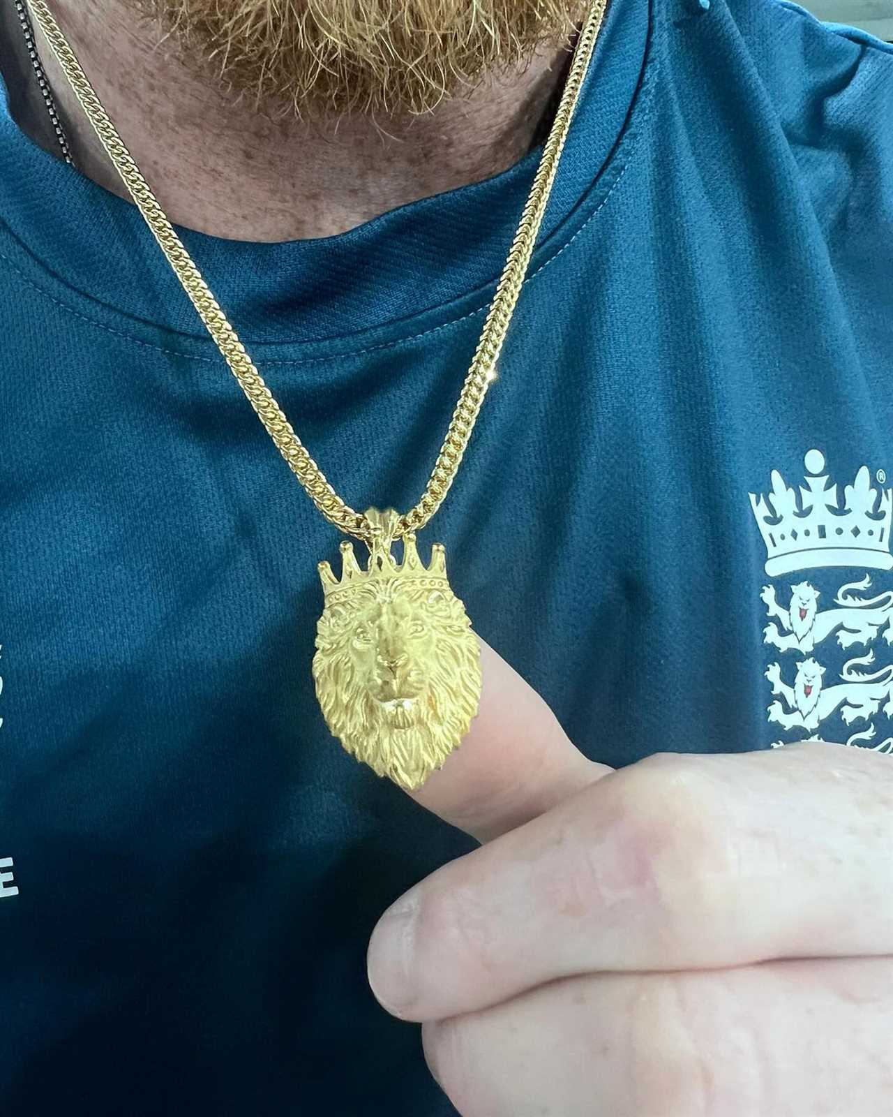 a man wearing a necklace with a lion head on it