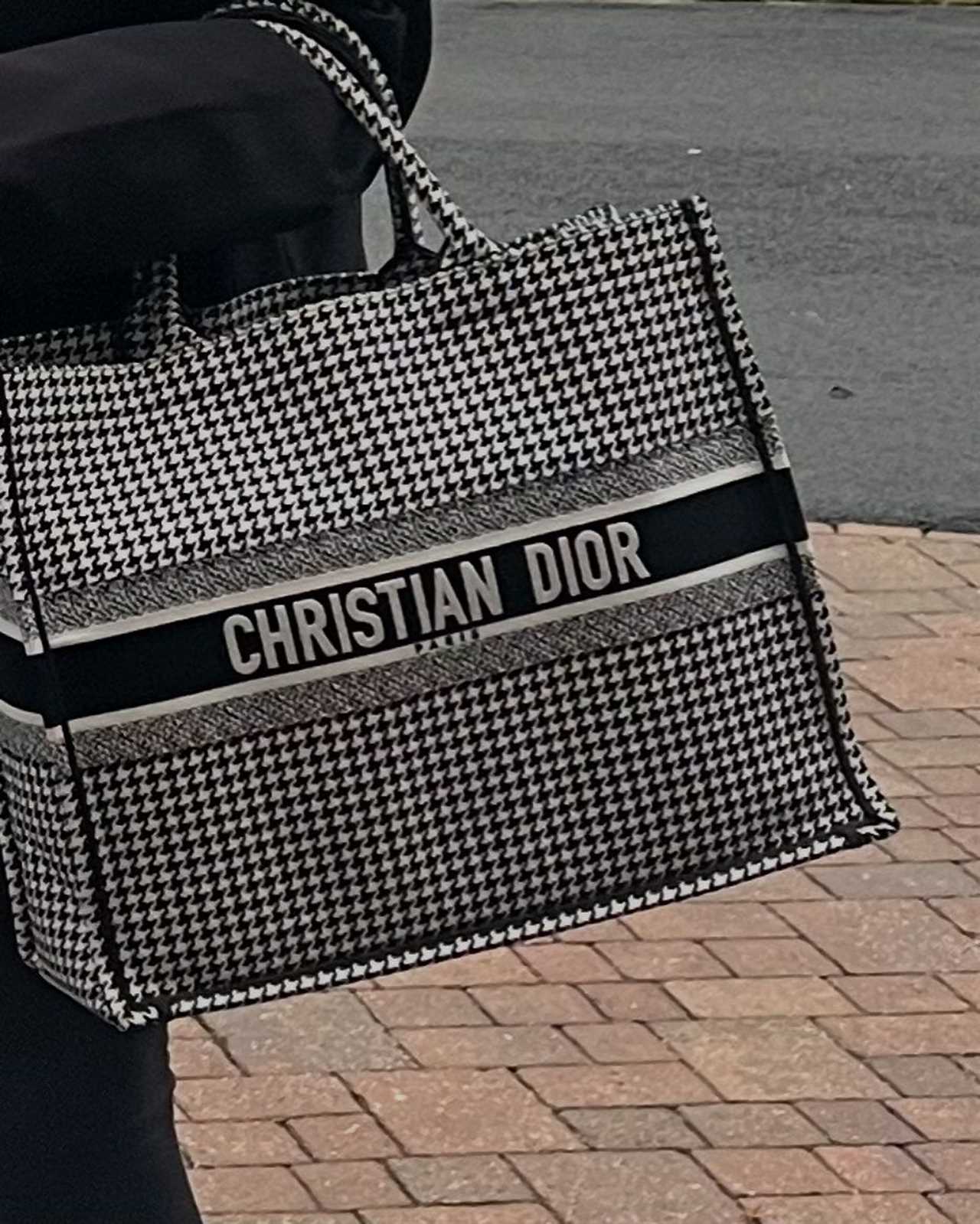 a person is holding a black and white christian dior bag