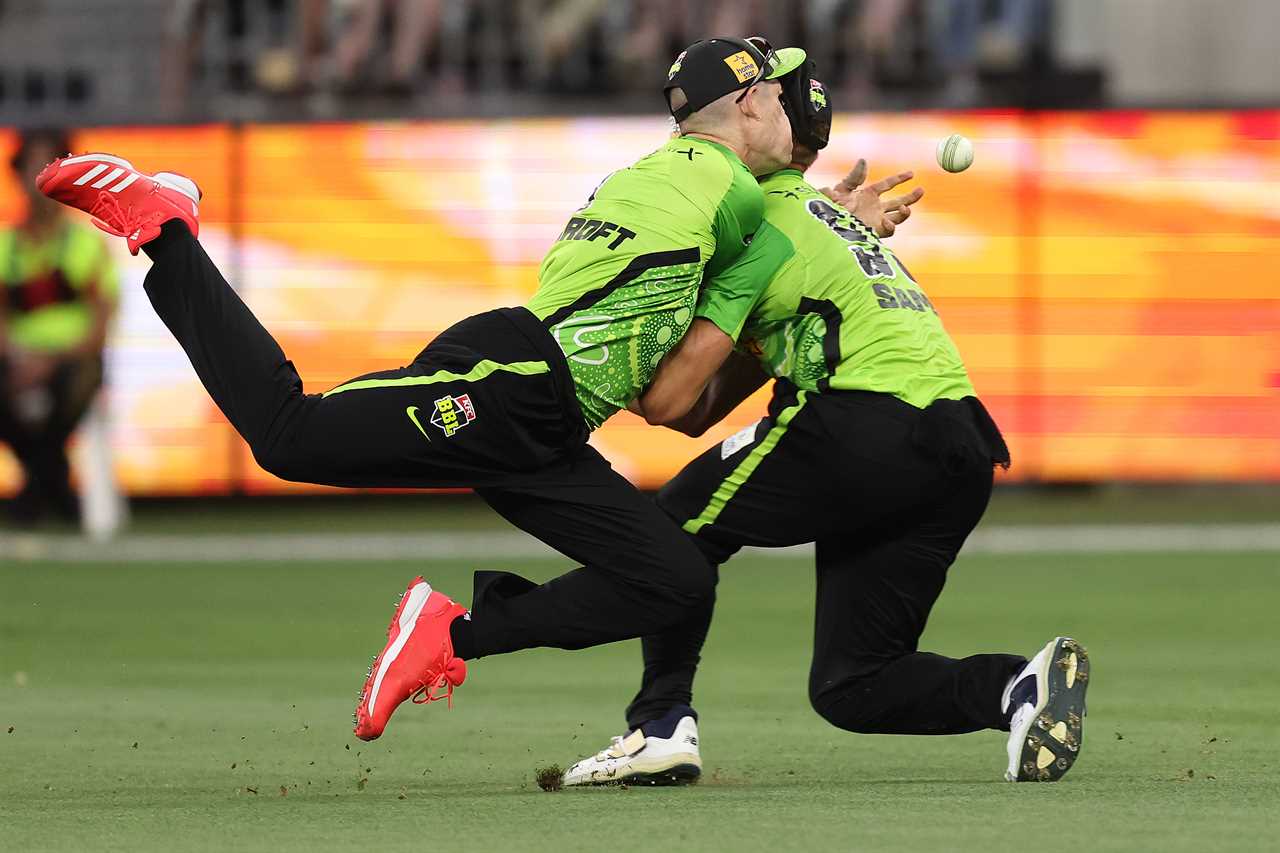 Two cricket players collide while attempting to catch a ball.