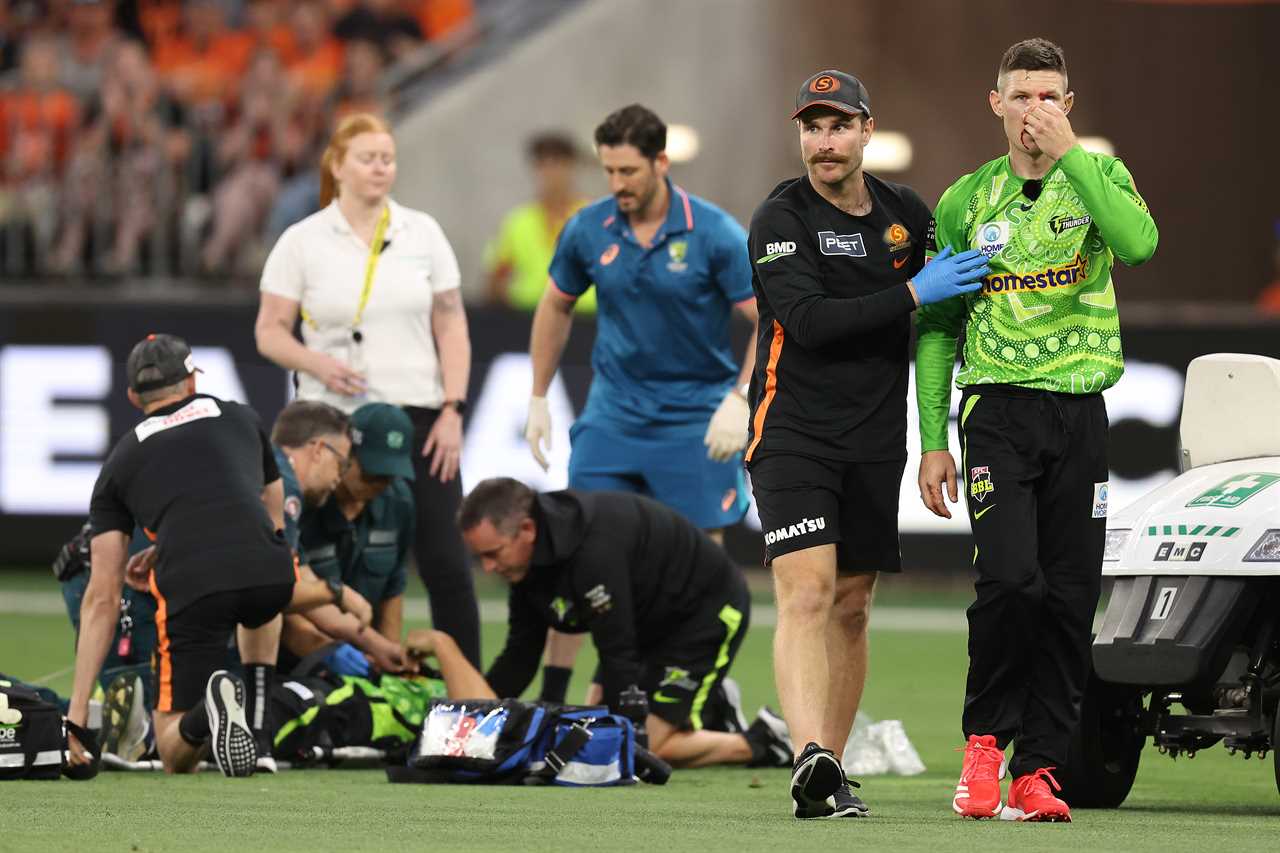 Injured cricket player assisted from the field.