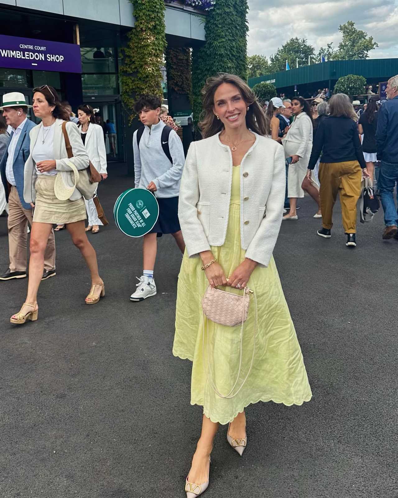 Woman in yellow dress and white jacket at Wimbledon.