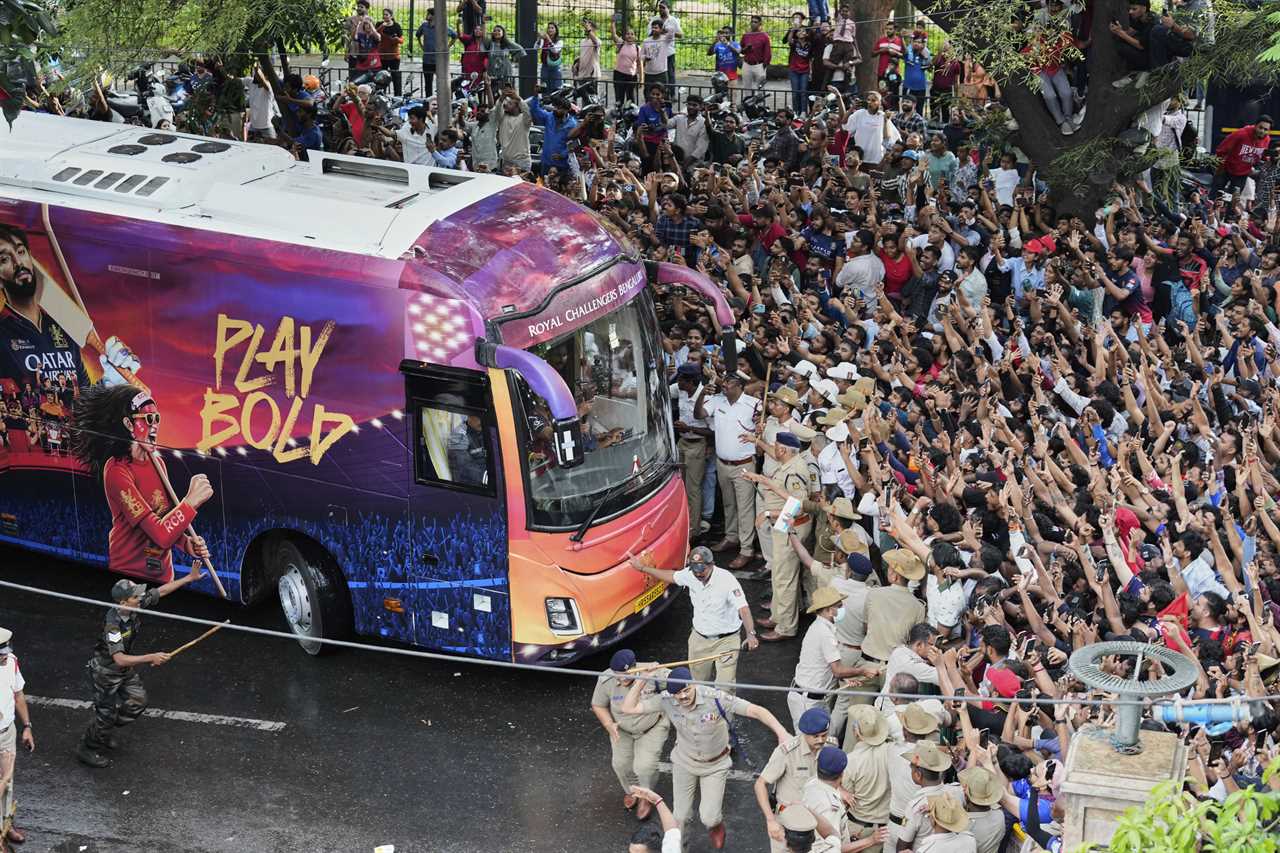 Fans cheering as a bus carrying the Royal Challengers Bengaluru cricket team arrives.