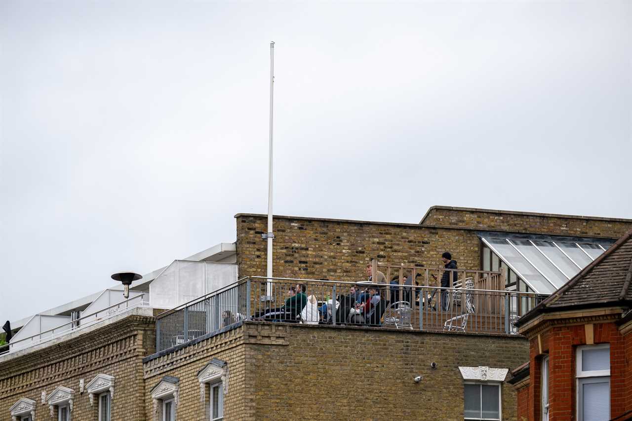 People enjoying a rooftop terrace overlooking The Oval cricket ground.