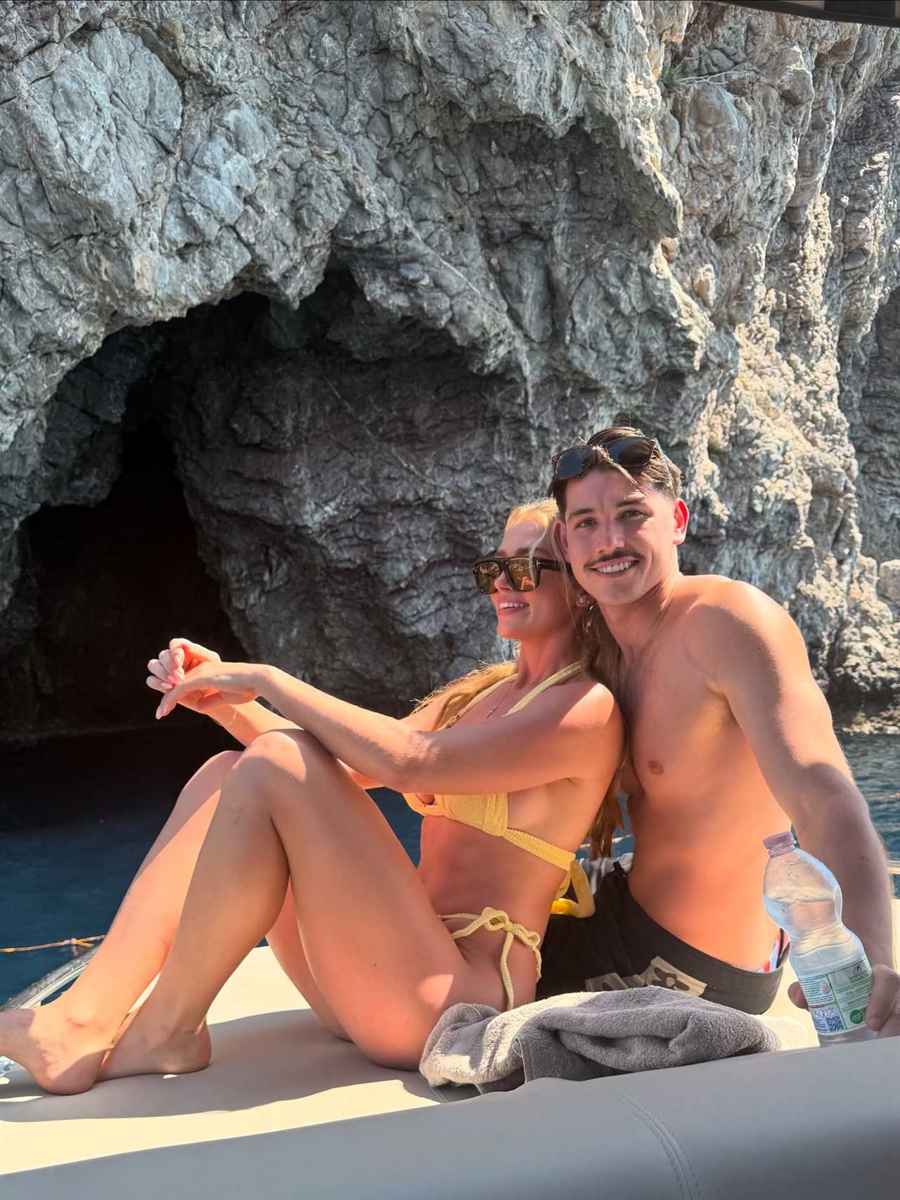 Couple sitting on a boat near a cave.