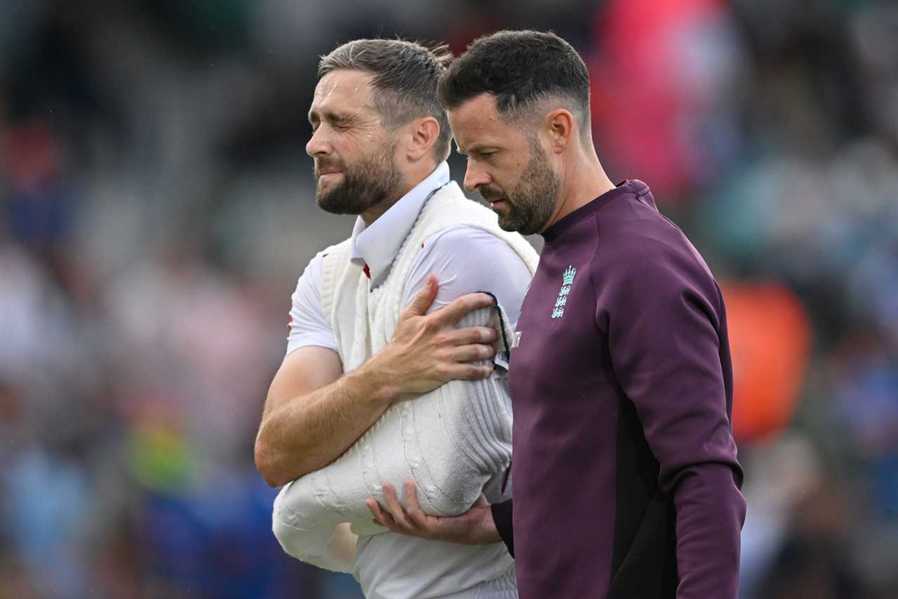 Chris Woakes of England with a shoulder injury being escorted from the field.