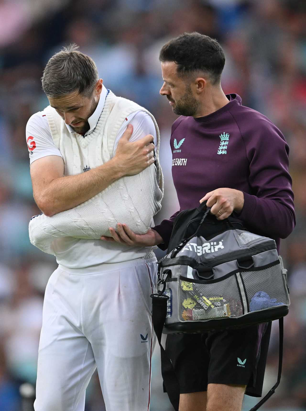 Chris Woakes of England is escorted from the field with a shoulder injury.