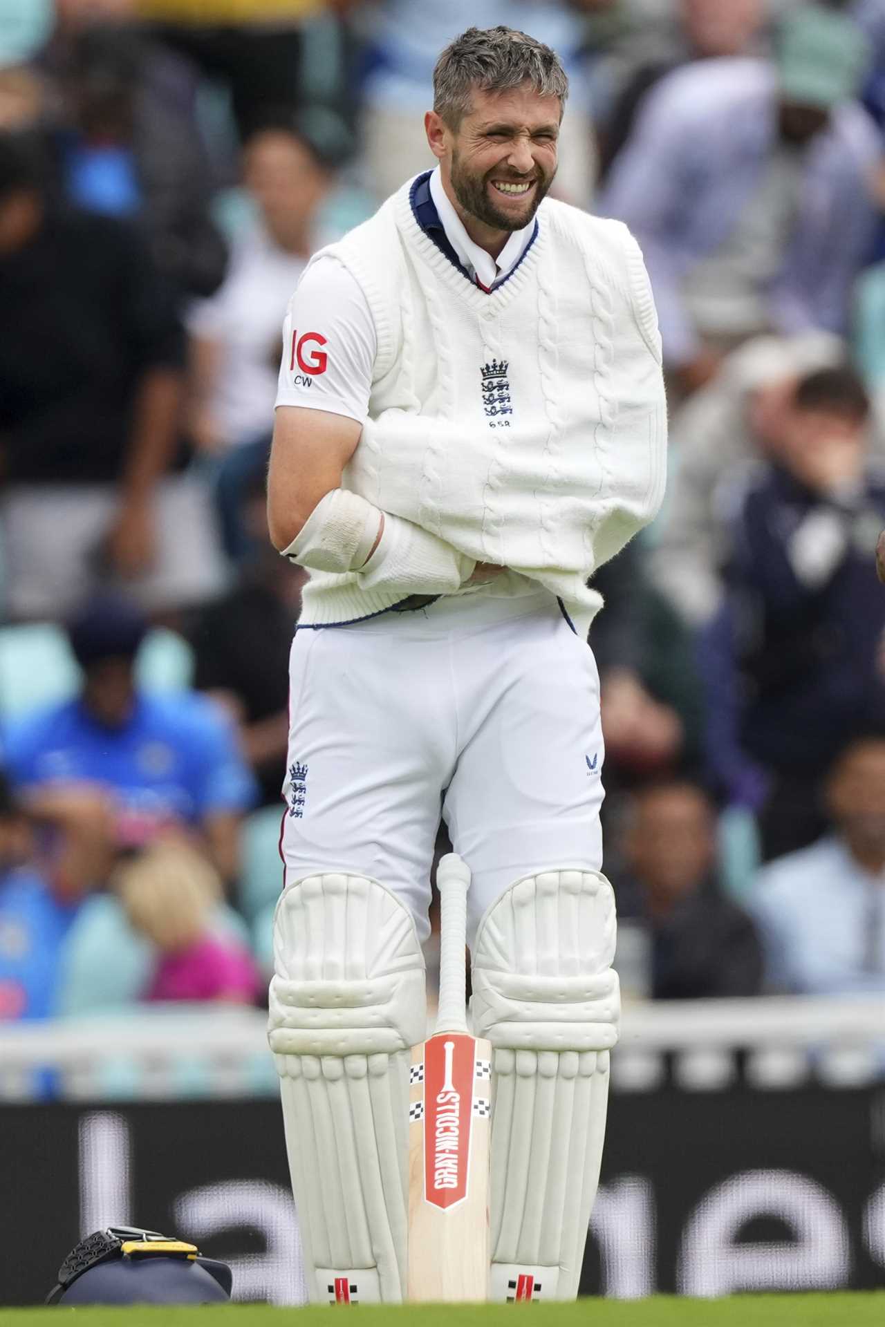 Chris Woakes, England cricketer, smiling while standing in cricket pads.