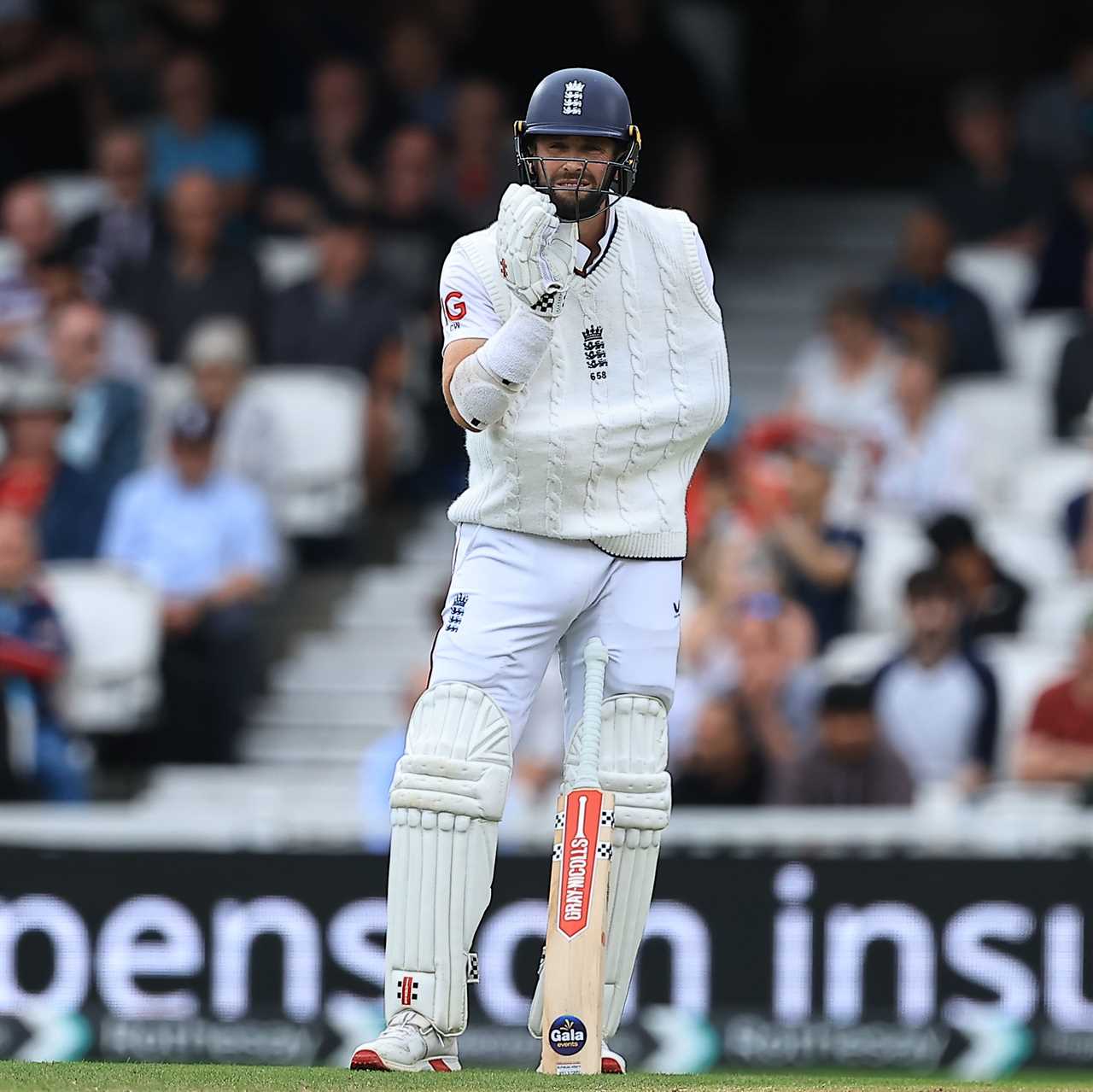 Chris Woakes walking onto a cricket pitch.