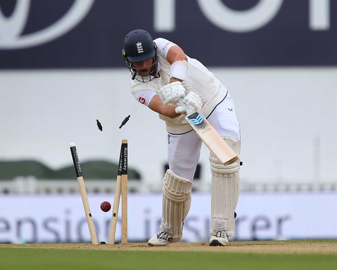 Cricket player batting, ball bowled, wickets knocked over.