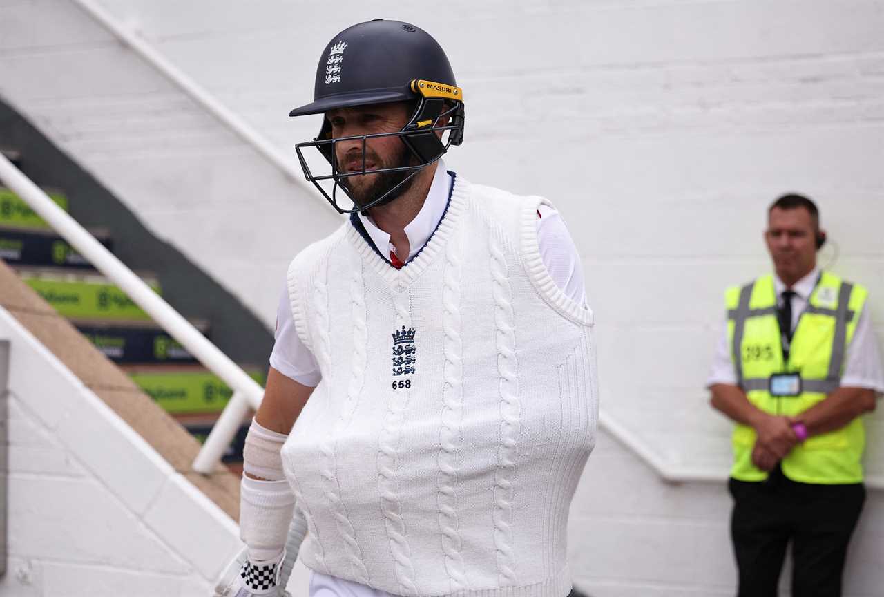 Chris Woakes walking onto a cricket pitch.