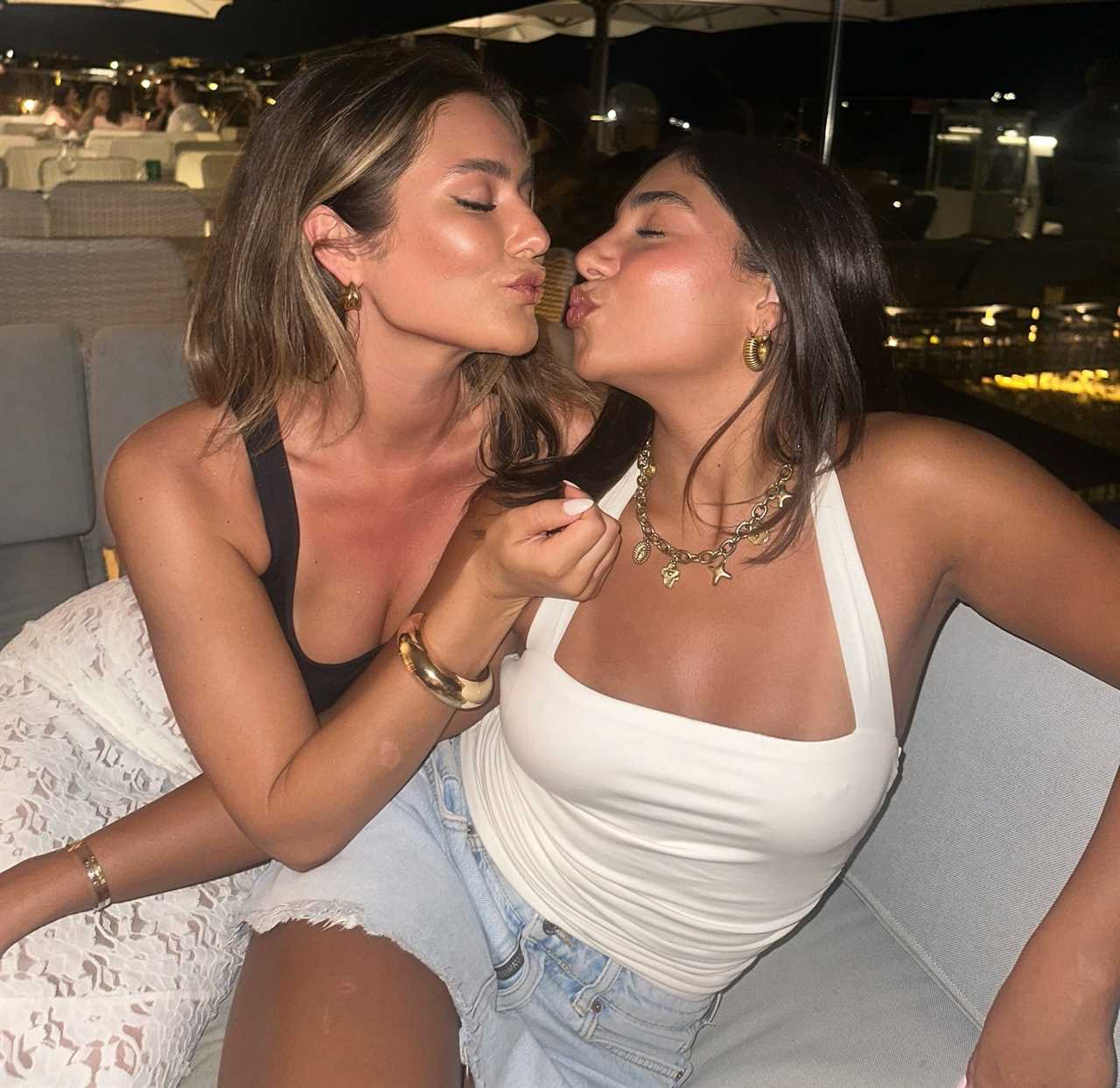 Two women kissing at an outdoor restaurant.